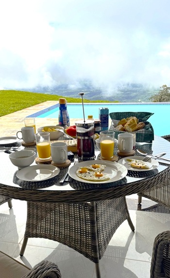 gedeckter Frühstückstisch agedeckter Frühstückstisch auf der Terrasse, Blick zum Pool und Wolken, die aus dem Tal aufsteigen