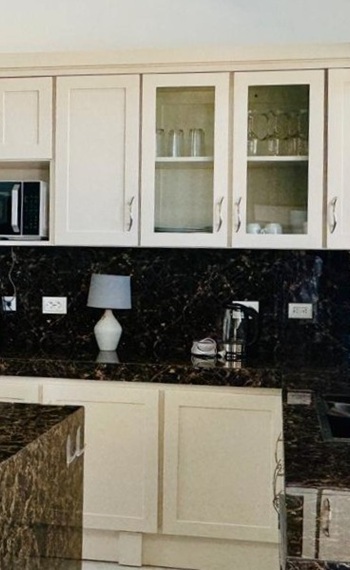 Küchenbereich mit Spüle, Kochinsel, Schränken und Kühlschrank