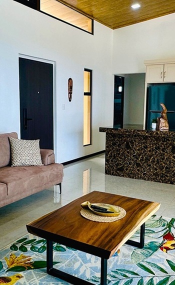 hoher, luftiger Raum mit Couch, Tisch und Küchenbereich