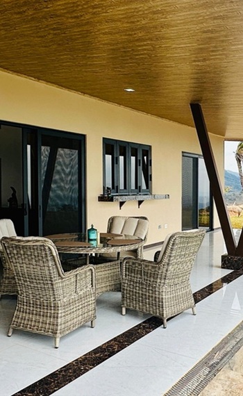 Sitzgruppe aus vier Korbstühlen und Tisch stehen auf der überdachten Terrasse